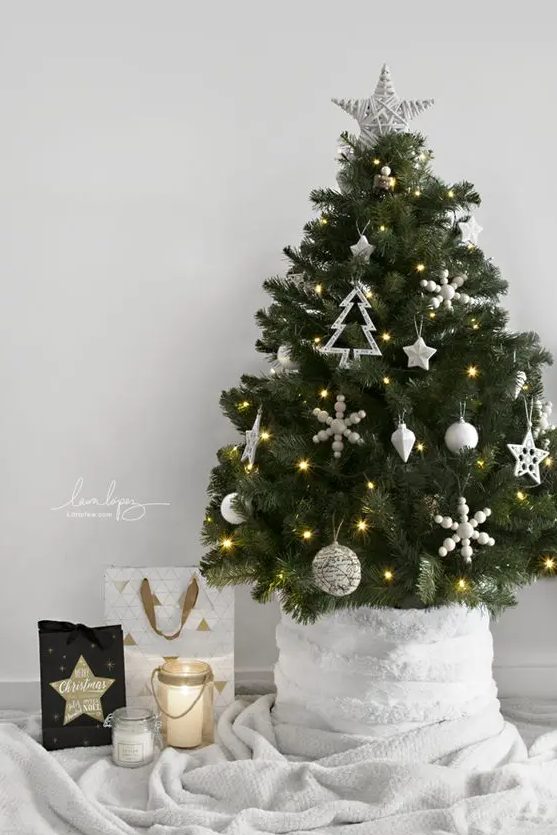a small Scandinavian Christmas tree decorated with white ornaments and lights is a cool and catchy idea