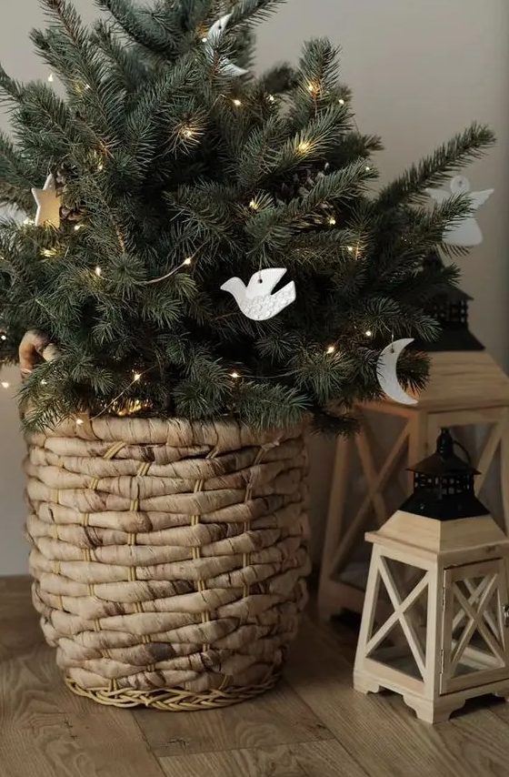 a small and pretty Christmas tree in a basket, with lights, white clay ornaments is a lovely decor idea for the holidays