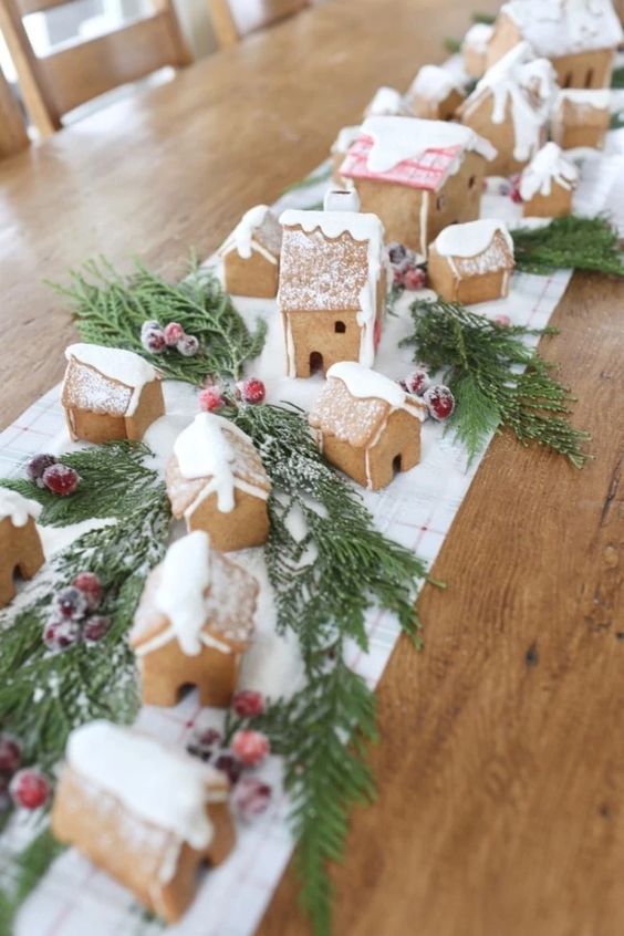 decorate your Christmas tea party table with a runner, gingerbread houses, evergreens and cranberries