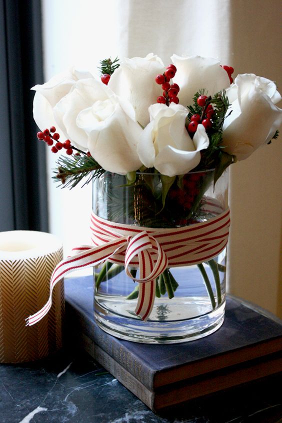 glass vase is classics, and white roses with red berries and evergreens it looks as a modern take on traditional