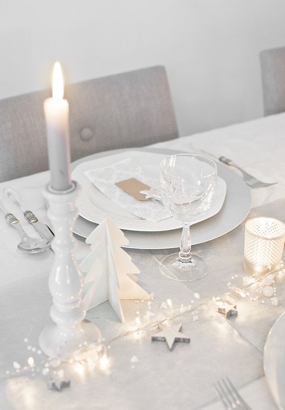 white Christmas table setting with lights, stars and candles
