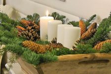 10 a large wooden bowl filled with pinecones, evergreens and pillar candles