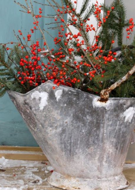 a galvanized bucket with evergreens and holly berries