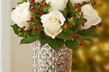 11 winter white roses are paired with festive red hypericum berries and put in a mercury glass vase