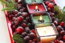 13 candles displayed on a tray with evergreens and cranberries