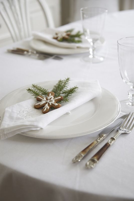 white Christmas table with gingerbread cookies and evergrene sprigs