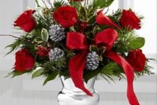 16 a silver vase with greenery, pinecones, red roses and ribbon bows
