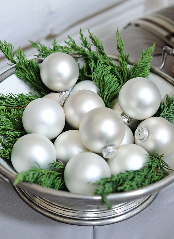 a silver bowl with pearl ornaments and evergreens