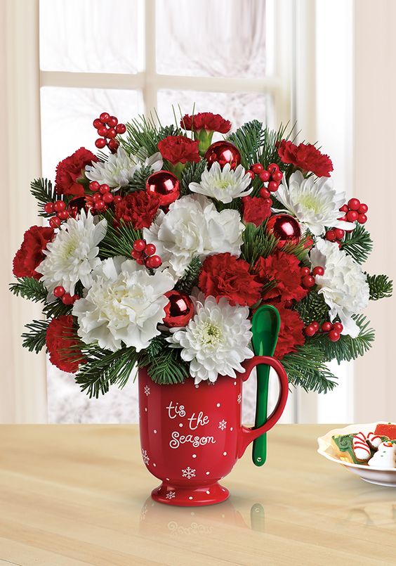 Hot cocoa mug with a lush green, red and white arrangement and a green spoon