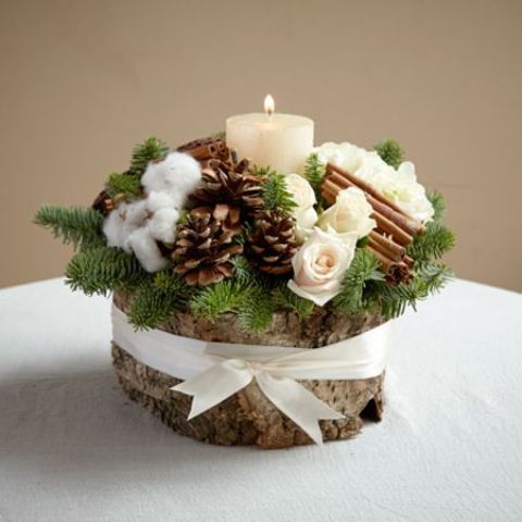 a wooden log with pinecones, evergreens, cinnamon sticks and a candle