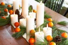 24 tangerines, pillar candles and evergreens on a mirror