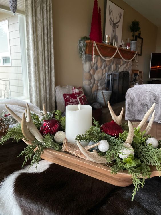 a Christmas dough bowl with evergreens, antlers, white and red ornaments and a pillar candle is amazing