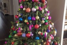 a Christmas tree decorated with colorful ornaments of various shapes and a gold star topper is amazing