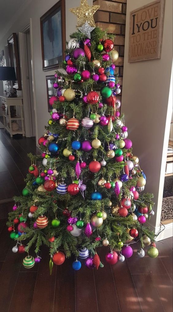 a Christmas tree decorated with colorful ornaments of various shapes and a gold star topper is amazing