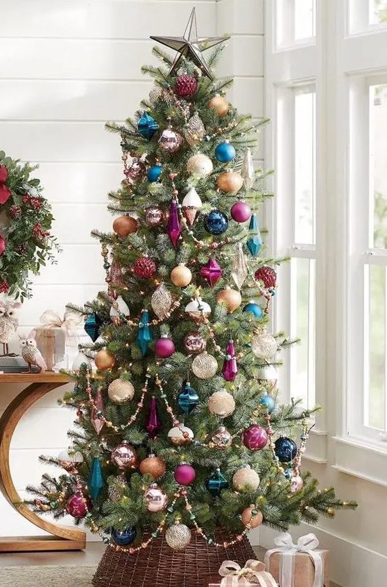 a Christmas tree decorated with colorful ornaments, purple, navy and teal ones, plus beaded garlands