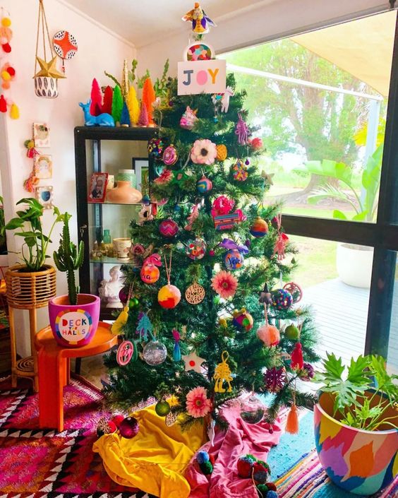 a Christmas tree with extra bold ornaments, baubles and paper ones and a sign on top is an amazing idea