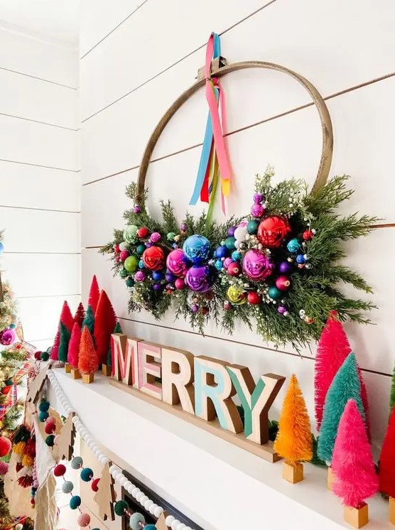 a bright Christmas mantel with wooden letters, colorful botle cleaner trees, a bold wreath with shiny and bright ornaments for Christmas
