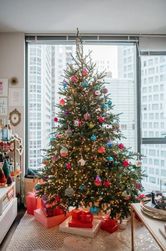 a bright Christmas tree with lights and colorful ornaments is a super catchy and cheerful decor idea