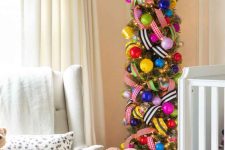 a bright pencil Christmas tree with colorful oversized ornaments and printed ribbons and lights is wow