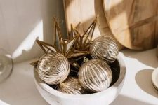 a catchy Christmas arrangement of a bowl with metallic ornamnets is a lovely solution