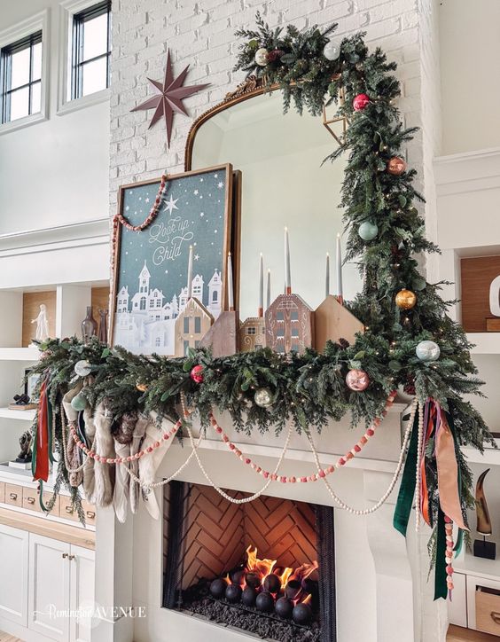 a chic Christmas mantel with evergreens and colorful ornaments, sotckings, beads and wooden houses