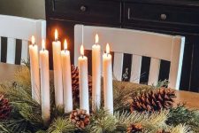 a classic woodland or rustic Christmas centerpiece of a wooden bowl with evergreens, pinecones and candles