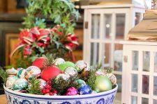 a colorful Christmas centerpiece of a blue printed bowl, colroful vintage ornaments, evergreens is a cool decoration