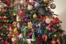 a colorful Christmas tree styled with bold lights, snowflakes, colorful ornaments, snowflakes and pinecones
