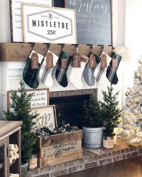 a farmhouse living room with plaid stockings, a crate with evergreens, mini Christmas trees and a neutral Christmas tree