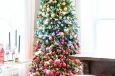 a faux Christmas tree decorated with ornaments of all shades possible forming a rainbow is a cool and bright decor idea for the holidays