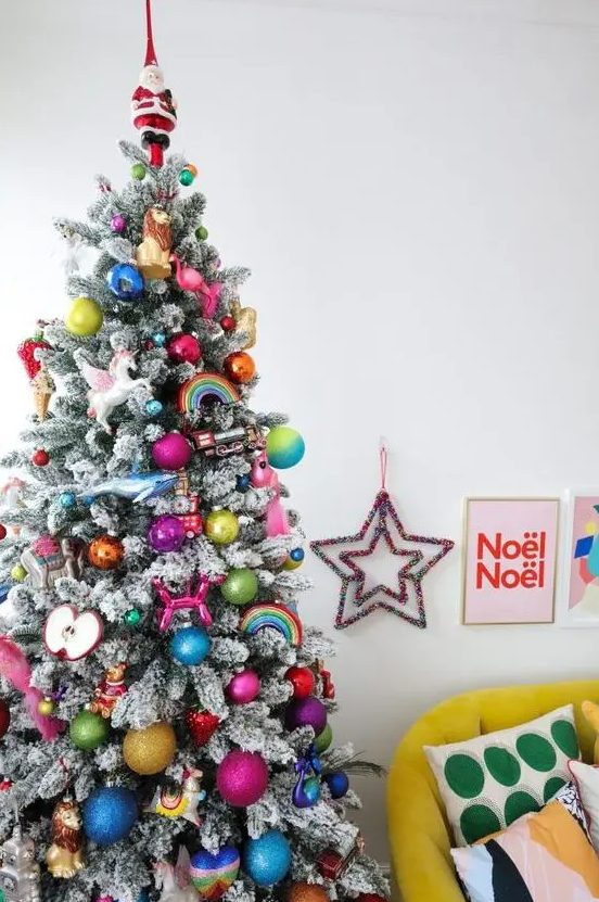 a flocked Christmas tree decorated in all the colors of the rainbow, with bold ornaments, rainbows, apples and a unicorn