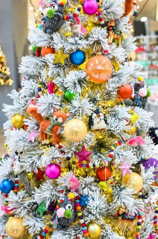 a flocked Christmas tree decorated with all kinds of colorful ornaments, beads, stars and toys is amazing