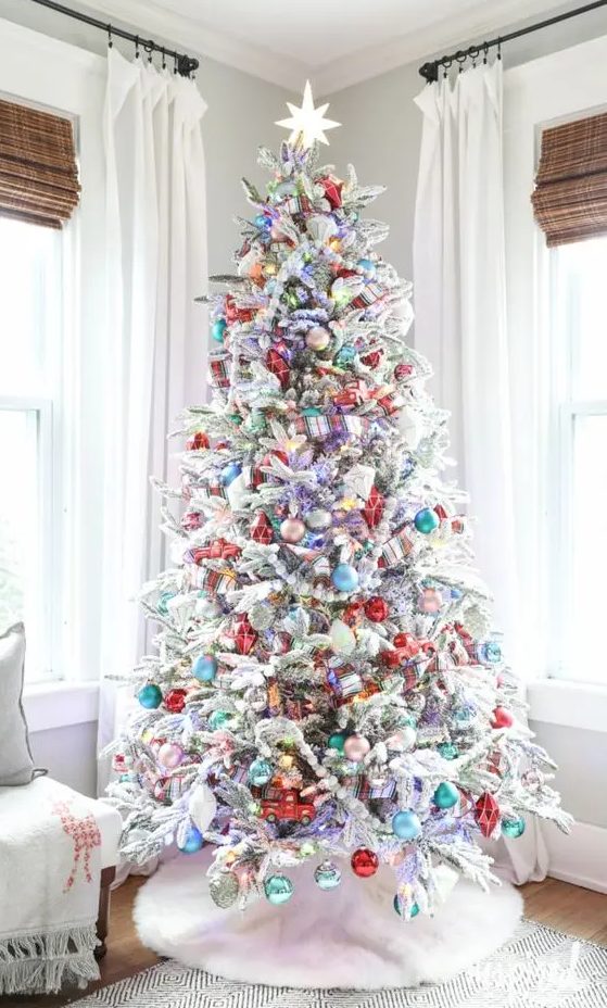 a flocked Christmas tree styled with bold ornaments and lights is a cool and catchy solution for a holiday space