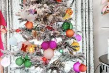 a flocked Christmas tree with bold ornaments and lights is a cool and chic decoration you’ll like