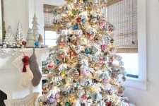 a flocked Christmas tree with colorful modern and vintage ornaments and lights is a stylish idea to rock