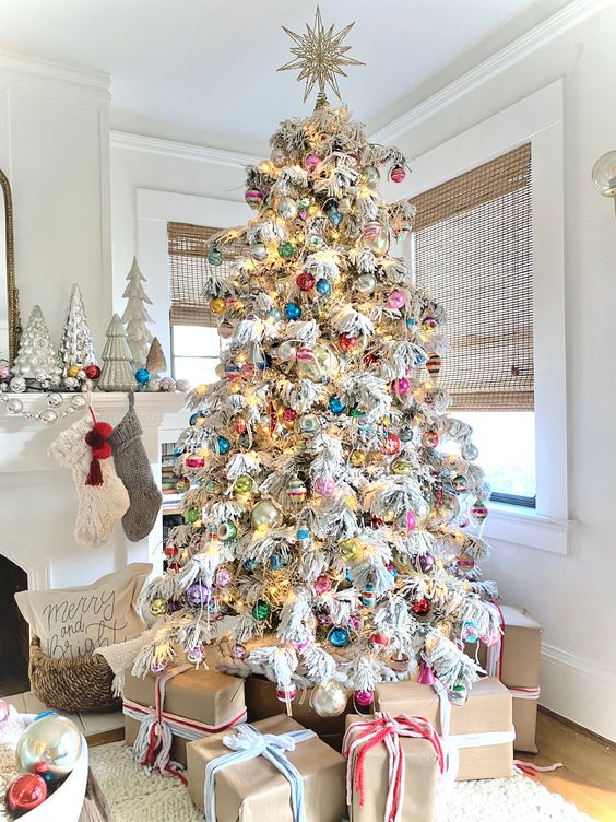 a flocked Christmas tree with colorful modern and vintage ornaments and lights is a stylish idea to rock