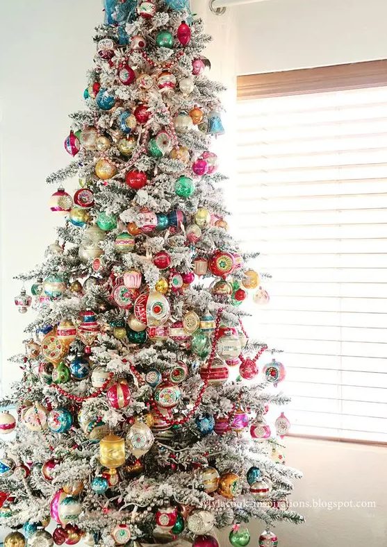 a flocked Christmas tree with colorful vintage ornaments is a lovely decor idea for the holidays