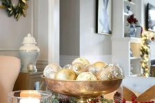 a glam Christmas centerpiece of a gold bowl with silver and gold ornaments and lights is a chic idea