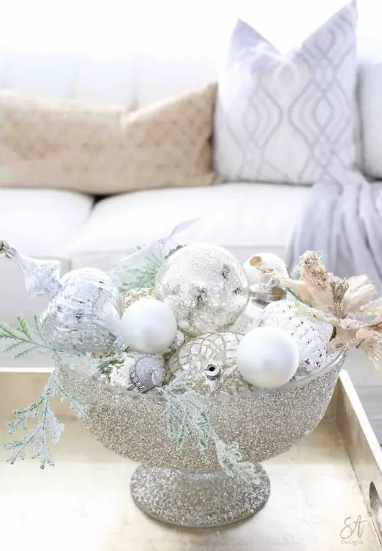 a glam Christmas centerpiece of a sivler glitter bowl, white and silver ornaments, evergreens is a cool idea
