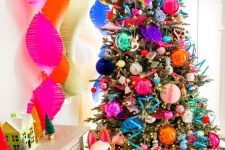 a holiday tree decorated with oversized colorful ornaments, paper ribbons and baubles looks super cool and bright