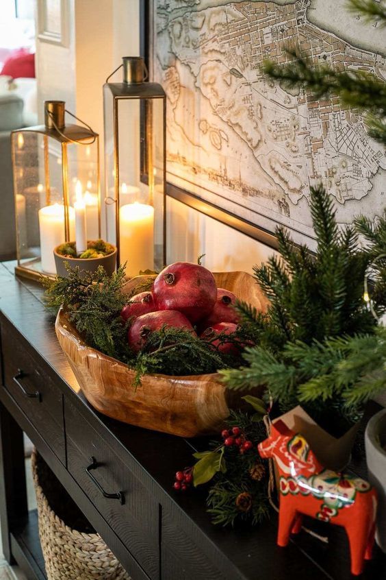 a large wooden bowl with evergreens and pomegranates is a cool and catchy decoration for the holidays