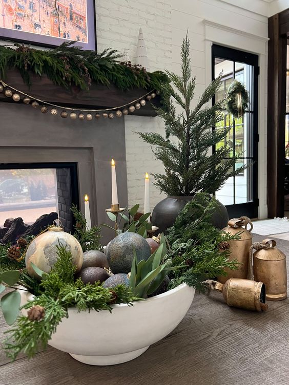 a lovely holiday arrangement of a white bowl with greenery and dark ornaments is a cool Christmas decoration