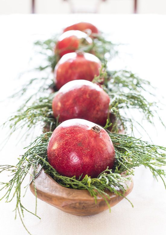 a natural holiday centerpiece of a dough bowl with evergreens and pomegranates is a lovely decor solution