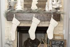 a pine garland with snowy pinecones, a pallet deer sign, Santa Claus dolls and white stockings