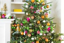 a pretty and bold Christmas tree with lights, green, orange and pink ornaments is a fun and cool solution