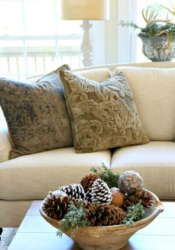 a rustic Christmas arrangement of a wooden bowl with vintage ornaments, pinecones and evergreens