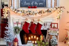 a ski lodge Christmas mantel with a snowy evergreen garland with red berries, a pompom garland, red stockings and mismatching signs