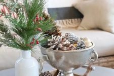 a small metal bowl with ornaments and snowy pinecones is a cool decor idea with an elegant feel