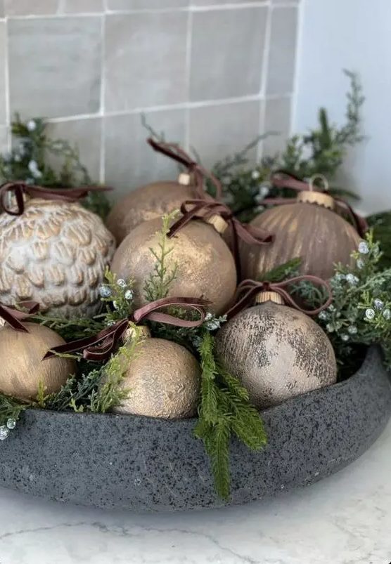 a stone bowl with evergreens and small white blooms plus vintage copper and gold ornaments is a lovely centerpiece