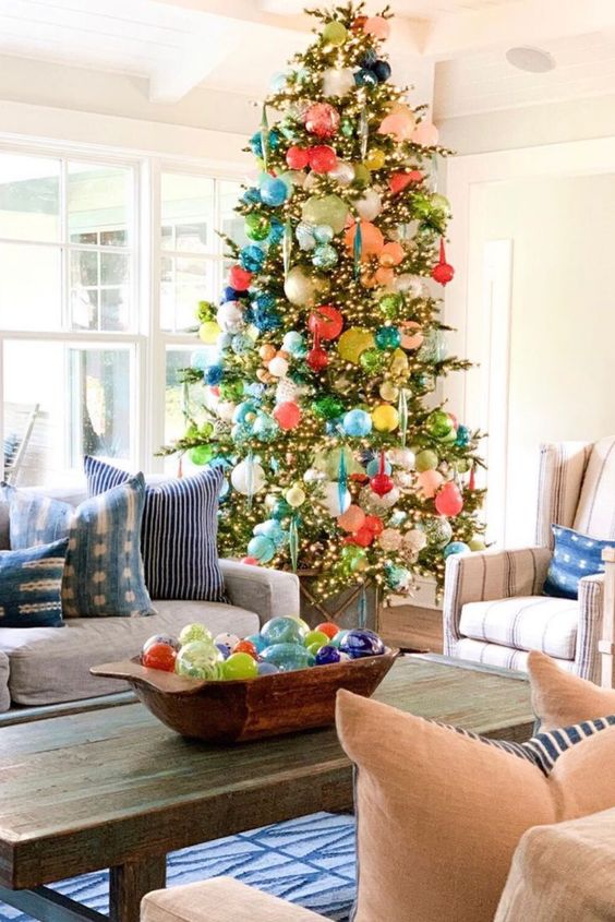 a tall Christmas tree covered with lights and lots of colorful ornaments of various shapes and sizes